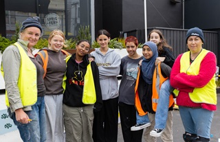 Group of people consisting of two adults and six students, all wearing high vis vests.