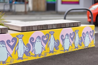 Penguins painted on the side of a bench.