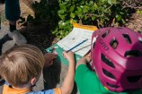 Two kids, one with a pencil filling out their treasure hunt form, the other wearing a bike helmet.