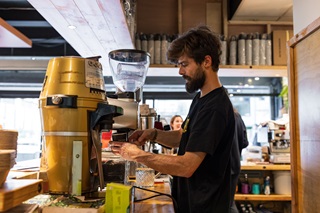 Person wearing a black tshirt making coffee.