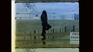 A person standing on top of a fence around a radio astronomical observatory.