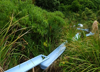 Watershed Sculpture - spouting pipes collecting water on a hillside.