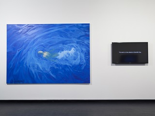 A blue painting of water with a woman swimming hangs on a wall next to a T.V.