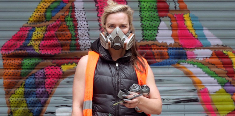 Close up of artist with paint cans and mask. 