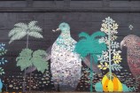 A mural on the side of the road that has colourful native birds and trees.