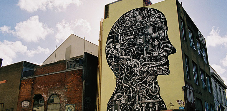 Black and white mural in illustrative style showing projector parts and forming a head shape.