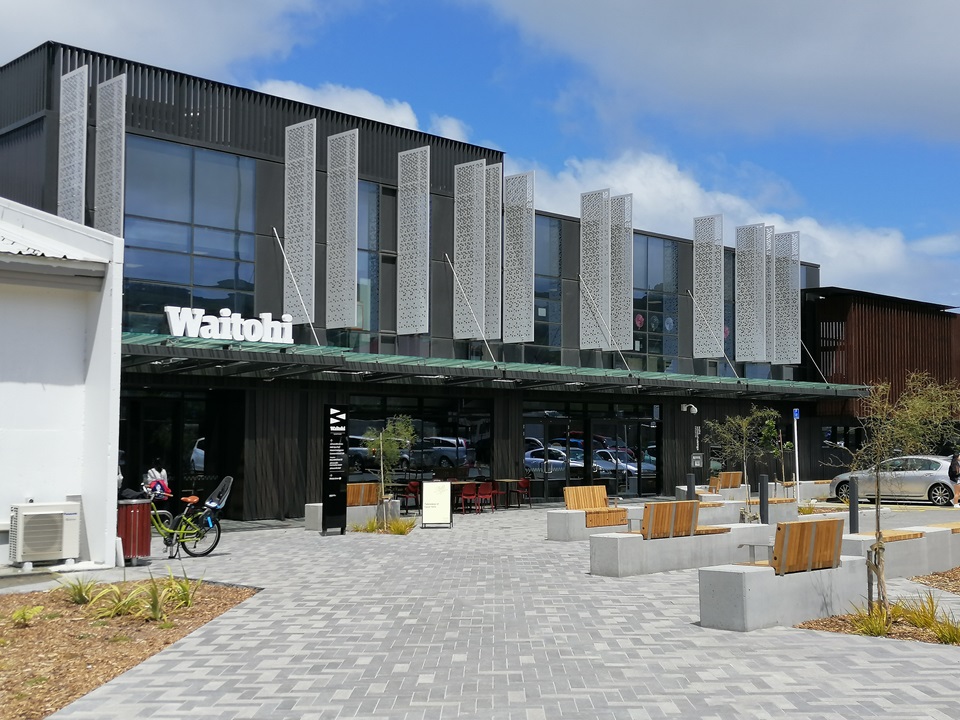 Photograph of the Waitohi Johnsonville Community Hub facade with seats and a bicycle in the courtyard.