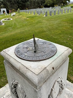 A metal sundial attached to the top of a marble pillar.