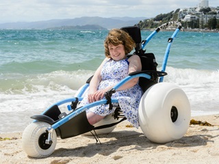A girl sits in the beach wheelchair at Oriental Bay.