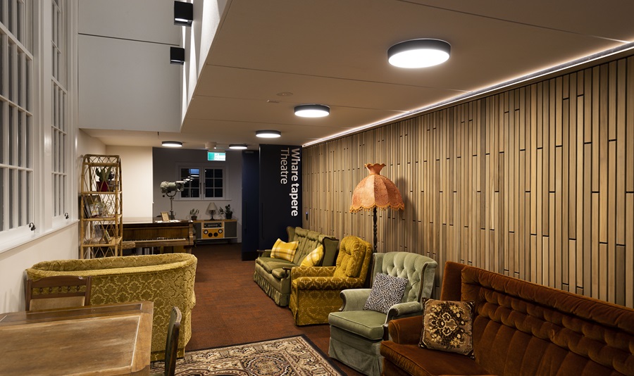 A lounge area with couches, a bookcase, a dining table and chairs and a lamp.