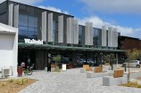 Photograph of the Waitohi Johnsonville Community Hub facade with seats and a bicycle in the courtyard.