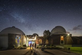 The exterior of Wellington Space Place lit up at night, with a starry open sky in the background.