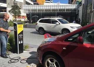 A sunny day with a man using the electric vehicle charger on Lombard Street, Wellington