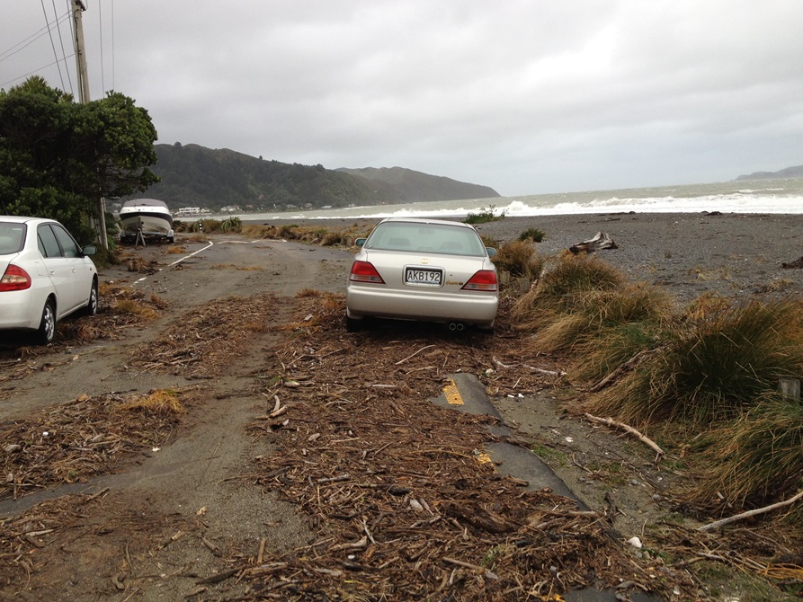 Cars parked among the debris on a stormy Ōwhiro Bay road