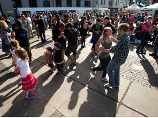 Kids and adults dancing salsa with large shadows due to the sunset.