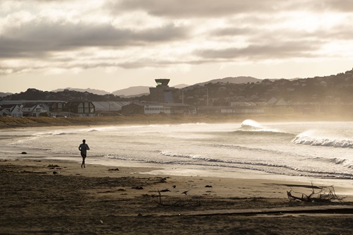 A man runs on a beach alone. 
