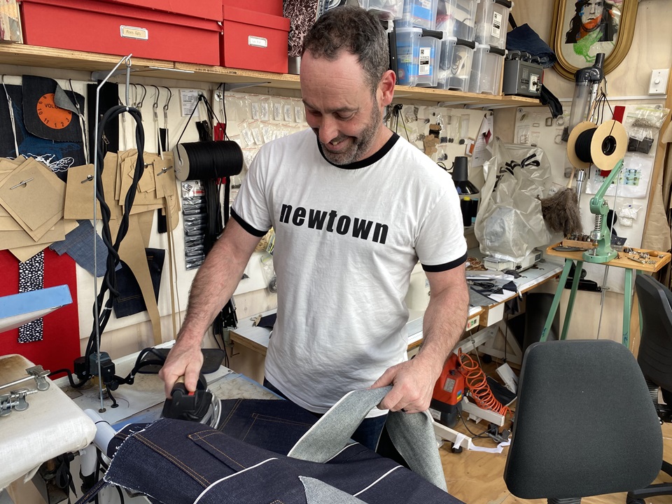Newtown-based clothing designer Duncan McLean ironing cut demin for jeans he is making in his workroom.