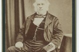 Photographic portrait of a man wearing a suit and waistcoast, posed in a seated position.