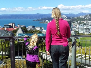 The back of a young girl and a women in a pink top with a long braid enjoying the view of Wellington from the top of the Cable Car track in Kelburn. 
