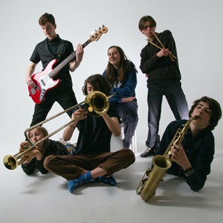 Six members of the teen jazz band Mel Stevenson, all posing in a white studio, holding their respective instruments.