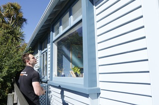Home Performance Advisor Craig Auty, from Sustainability Trust, assessing a light blue house on its energy consumption.