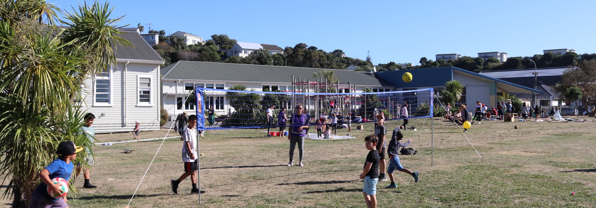 Children playing on the field with a volleyball net and classrooms in the background at Kahurangi School in Strathmore.