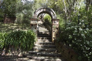 A historic stone archway and path surrounded in bush at Truby King Park.