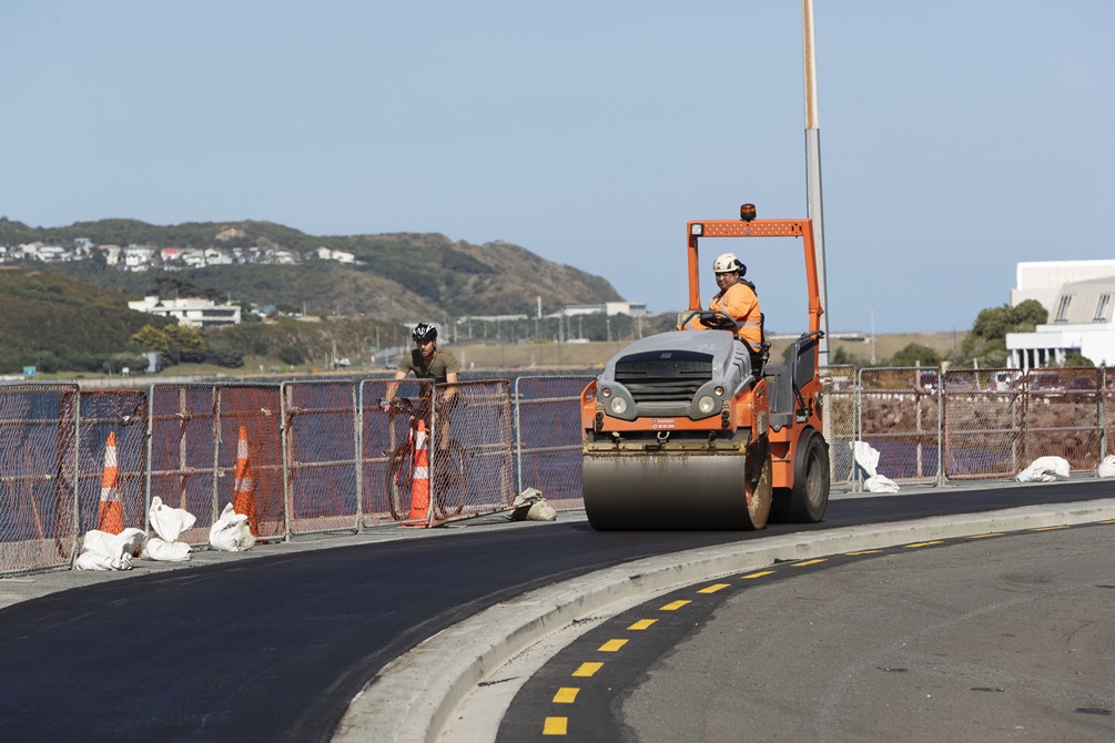 A workman on a roller laying a new asphalt path around Kio Bay.