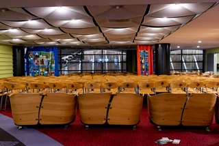 A huge number of wooden chairs lined up closely together in neat rows in the children's section of the library.
