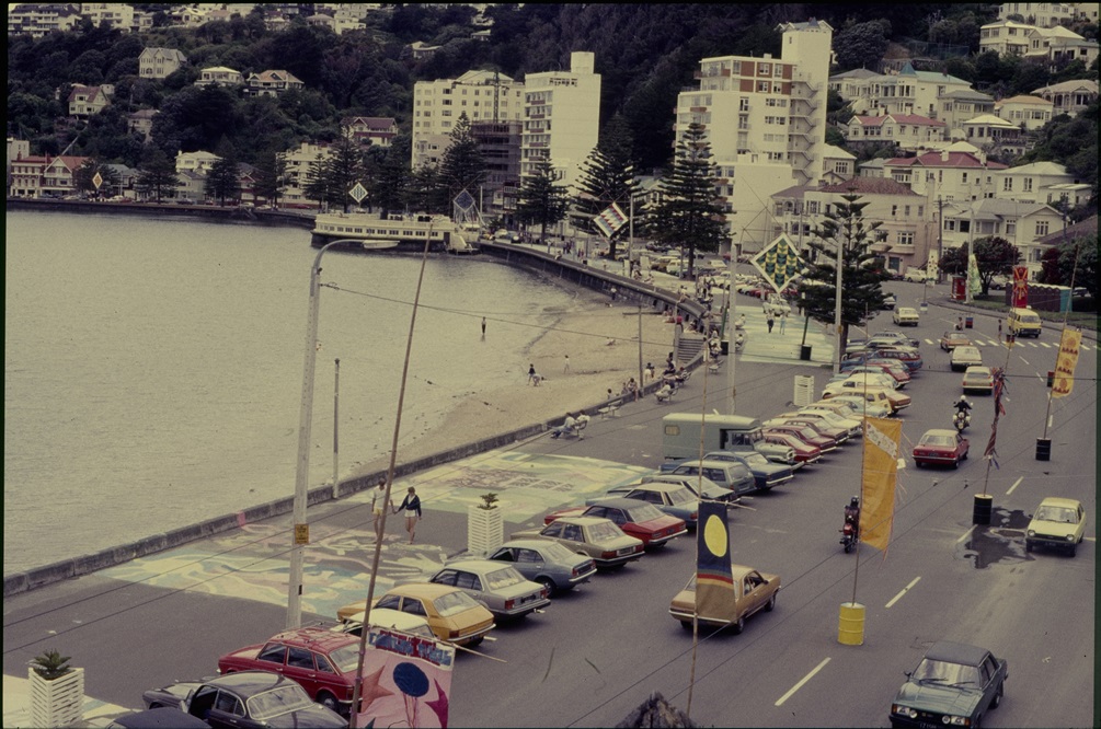 Oriental Bay full of retro cars with Summer City street flags hanging above it.