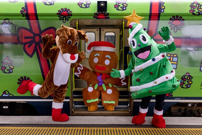 Roaming festive performers celebrate train wrapped in Christmas decorations