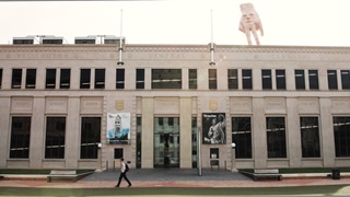 The cream stone Wellington City Gallery building, with tall dark rectangle windows, and a large hand sculpture on the roof.
