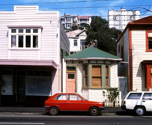 A red car parked outside a small wooden house wedged between too larger wooden houses on Aro Street in 1991. 