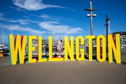 Well_ngton sign on waterfront with person demonstrating how to be the I in Wellington