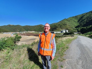 Stefan wearing a hi-vis vest standing in front of the Southern Landfill.