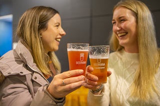 Two people smiling and sharing a beer.