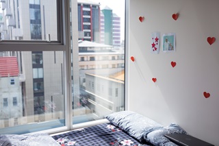 Bed infront of a window, with a view of the city.