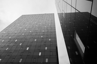A black and white image of two high rise buildings towering into the sky.