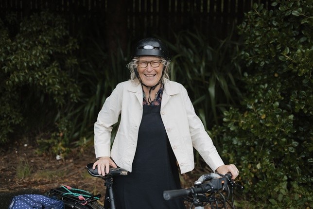 Woman standing behind her bike and smiling.