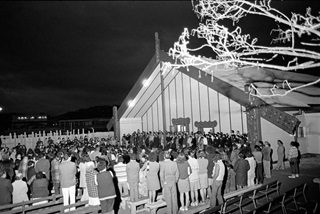A black and white photo of a marae with people gathered out the front.