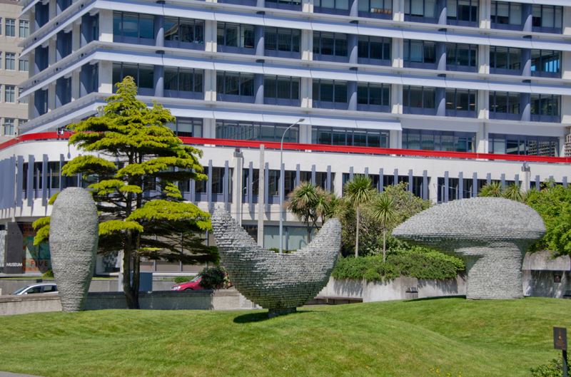 Three sculptures on the grass infront of a building.