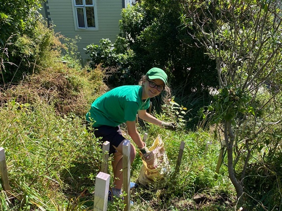 A teenage girl working in a garden wearing a green shirt.