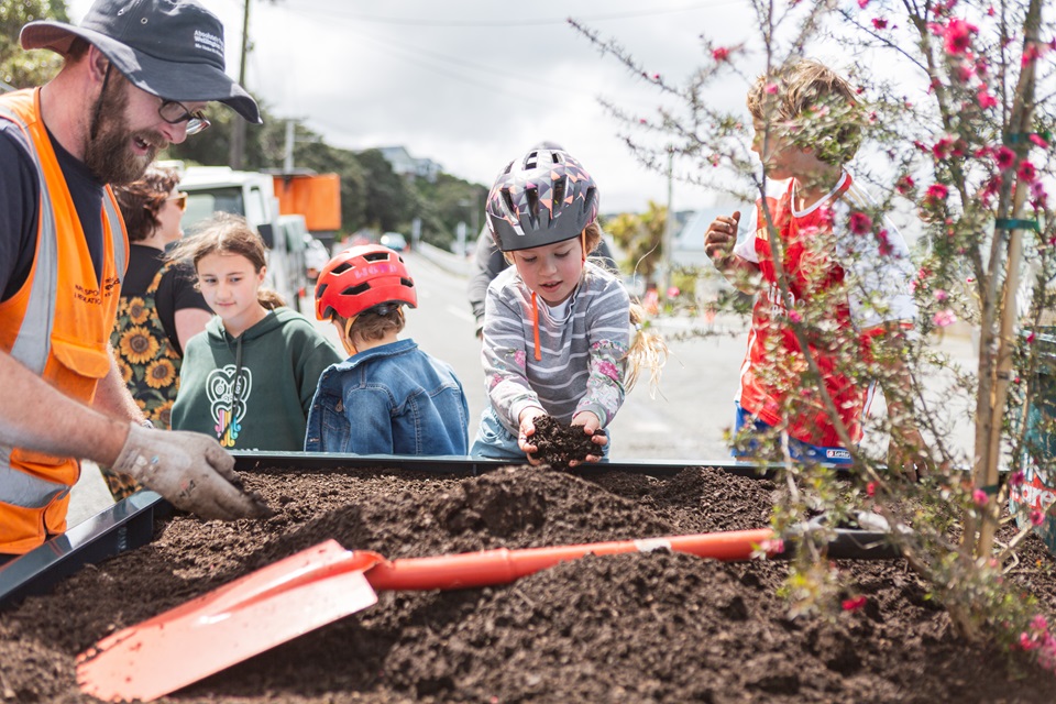 Child plants in planter box at launch of Lyall Bay street trial