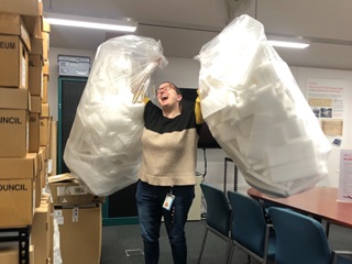 Woman holding up two big bags of foam.
