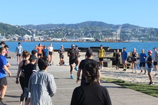 Group of people warming up to go on a run by the beach.