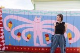 Person standing infront of a mural with a pink creature holding icecreams.