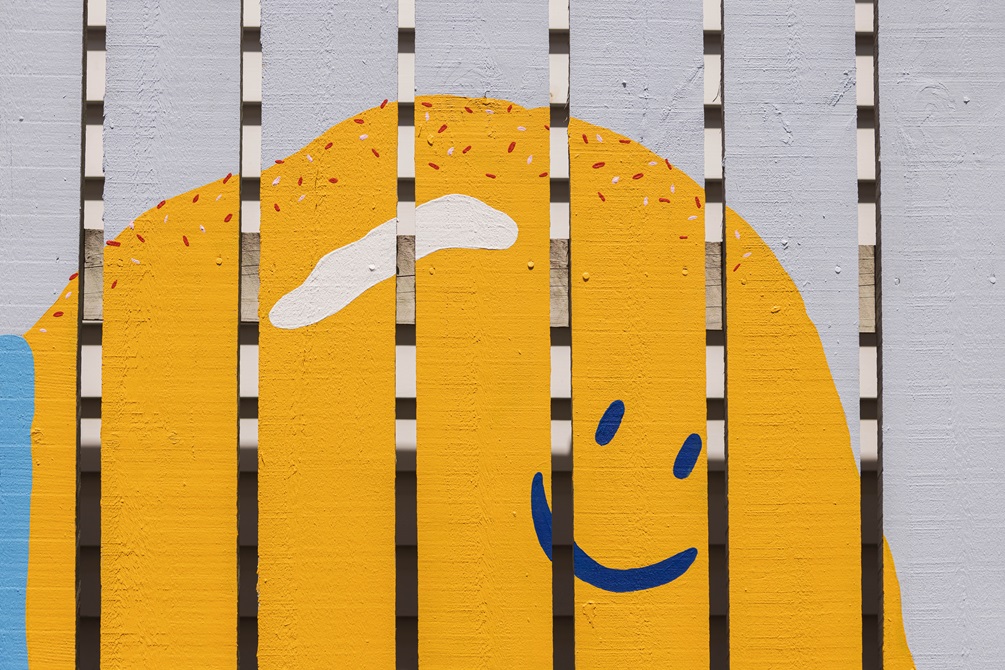 Yellow creature pained onto a fence.
