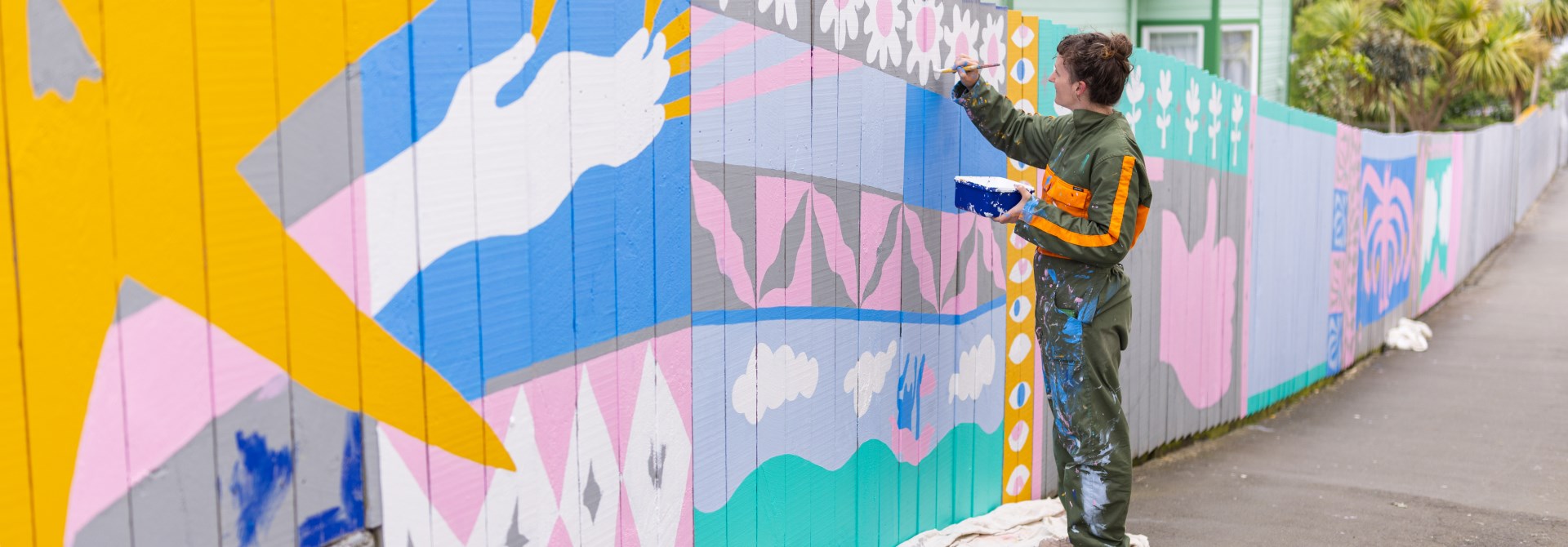 Person painting a mural wearing a jumpsuit.