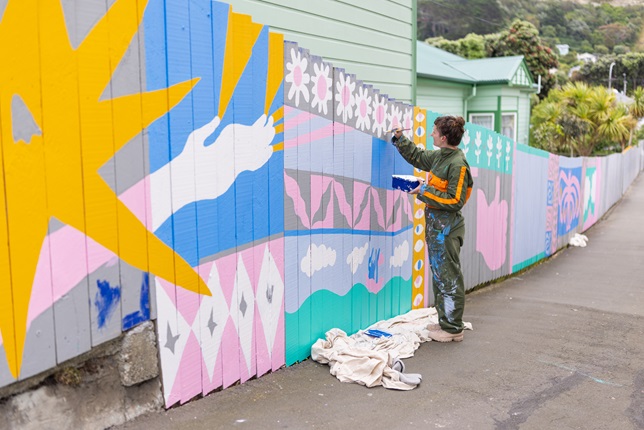 Person painting a mural wearing a jumpsuit.