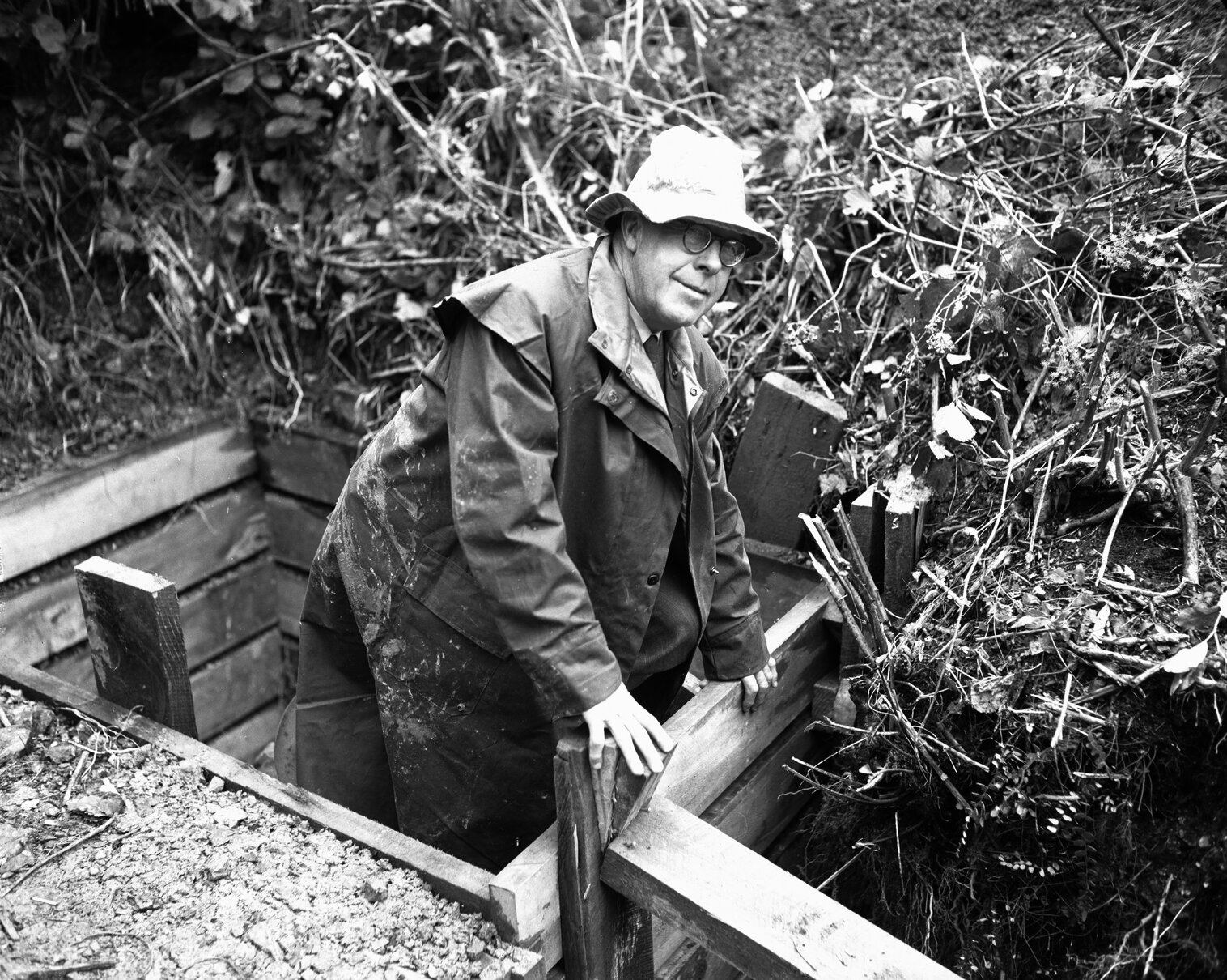 Sar Street sewage tunnel with a man climbing out of it wearing a trenchcoat and hat.